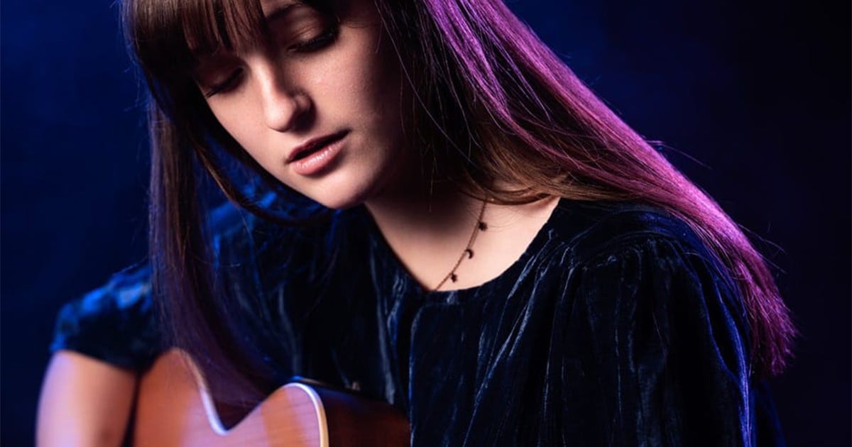 Laléa jouant de la guitare, le regard baissé avec concentration.