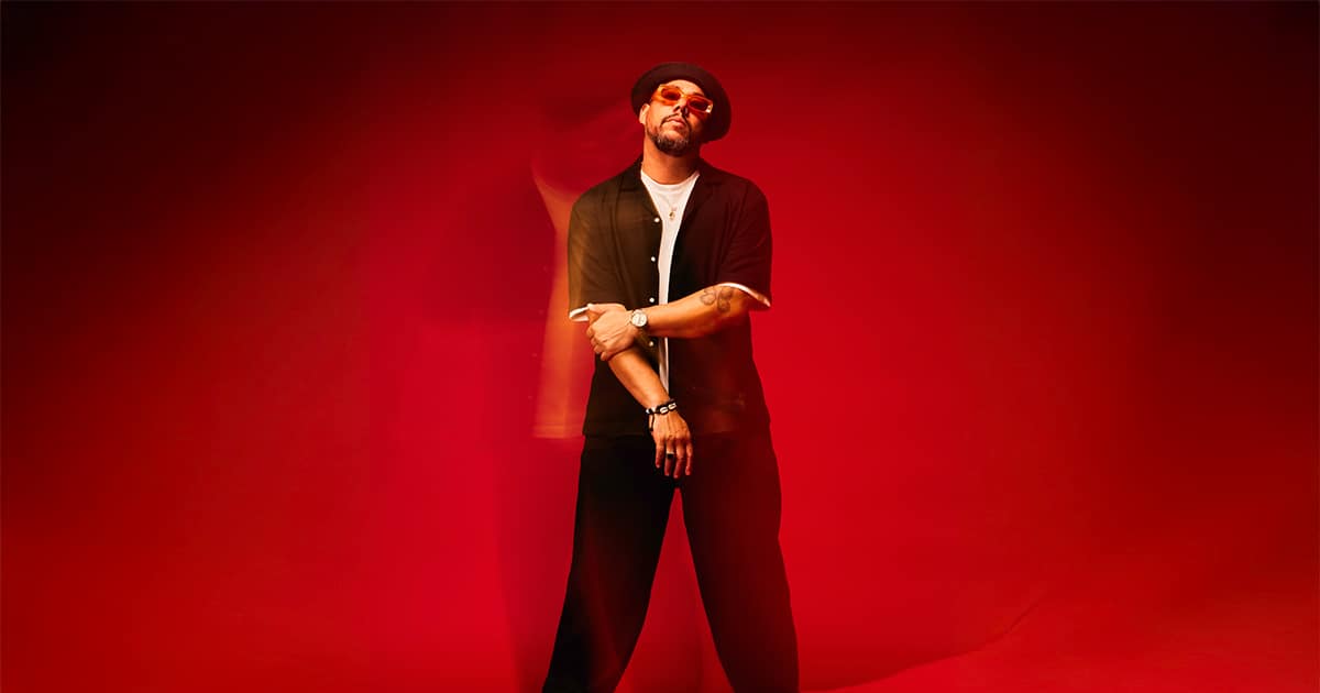 Ben l’Oncle Soul posant devant un fond rouge illuminé d’effets de lumière.