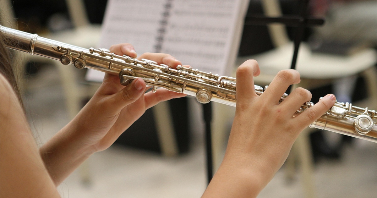 Mains jouant de la flûte traversière, en gros plan.