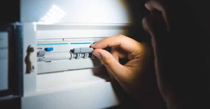Gros plan sur une main appuyant sur un bouton d’un compteur électrique.